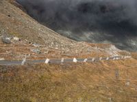 the sky is cloudy over a mountain with clouds in it, and sheep on the ground