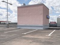 a large pink building sitting on the side of a road next to parking spots and grass