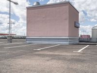 a large pink building sitting on the side of a road next to parking spots and grass