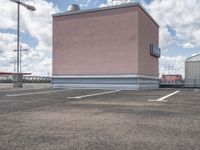 a large pink building sitting on the side of a road next to parking spots and grass