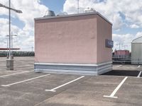 a large pink building sitting on the side of a road next to parking spots and grass