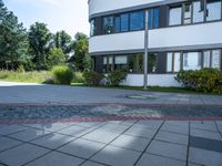 a building with a paved driveway and grass and plants in front of it in the daylight