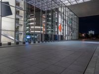 a very big square with some stairs and windows at night time with a fire hydrant sitting in front of it