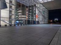 a very big square with some stairs and windows at night time with a fire hydrant sitting in front of it