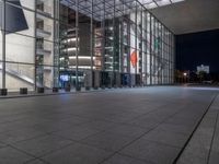 a very big square with some stairs and windows at night time with a fire hydrant sitting in front of it