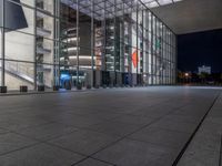 a very big square with some stairs and windows at night time with a fire hydrant sitting in front of it