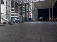 a very big square with some stairs and windows at night time with a fire hydrant sitting in front of it