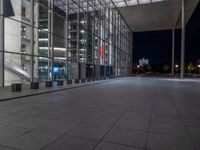 a very big square with some stairs and windows at night time with a fire hydrant sitting in front of it