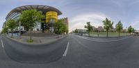 a city with an intersection of road and building with street lights above it in a 360 - fisheye view