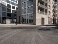 buildings and street signs are reflected in this photograph of a street lined with parked cars