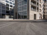 buildings and street signs are reflected in this photograph of a street lined with parked cars