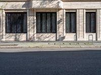 a man walking along a street past a brick building with windows and a fire hydrant