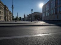 a street light next to an empty road in front of a building with a traffic light on top of it