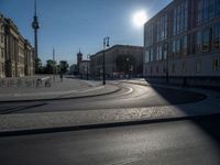 a street light next to an empty road in front of a building with a traffic light on top of it