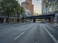 a city street that has a bridge over the road at sunset on a clear day