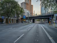 a city street that has a bridge over the road at sunset on a clear day