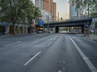 a city street that has a bridge over the road at sunset on a clear day