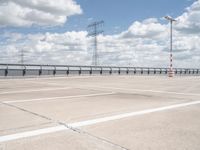 an empty parking lot with several electric towers above it and water below in the distance