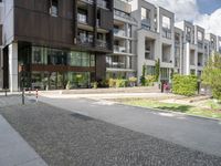 an asphalt street in front of apartment buildings and a bicycle path with cobblestone paved pavement