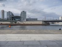 a building on the other side of the water is near by a bridge in a city