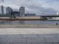 a building on the other side of the water is near by a bridge in a city