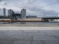 a building on the other side of the water is near by a bridge in a city