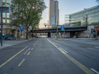 a city street that has a bridge over the road at sunset on a clear day