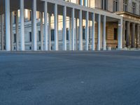 empty street lined with cement buildings next to a tall building with a staircase up to it