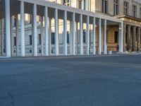 empty street lined with cement buildings next to a tall building with a staircase up to it