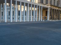 empty street lined with cement buildings next to a tall building with a staircase up to it