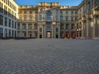 a courtyard with a building on the other side and a large white building with many windows