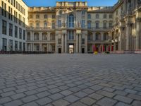 a courtyard with a building on the other side and a large white building with many windows