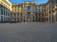 a courtyard with a building on the other side and a large white building with many windows