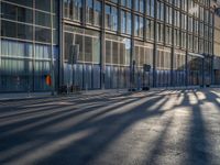 the sunlight reflects from several windows in a large building onto the street from outside the building