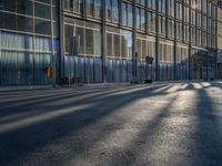 the sunlight reflects from several windows in a large building onto the street from outside the building