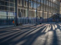 the sunlight reflects from several windows in a large building onto the street from outside the building