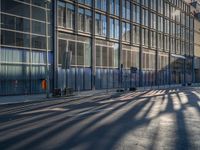 the sunlight reflects from several windows in a large building onto the street from outside the building