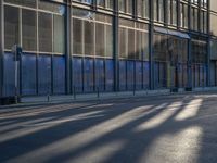 the sunlight reflects from several windows in a large building onto the street from outside the building