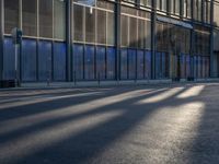 the sunlight reflects from several windows in a large building onto the street from outside the building