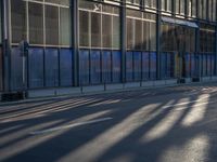 the sunlight reflects from several windows in a large building onto the street from outside the building