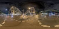 a view through a fish eye lens at night from the corner of a road in front of buildings