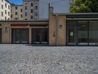 the sidewalk is paved with stones and has a bench in front of it, with no people inside