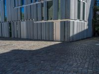 cobblestone driveway surrounded by modern buildings on sunny day with sun reflecting onto the windows