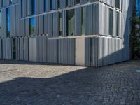 cobblestone driveway surrounded by modern buildings on sunny day with sun reflecting onto the windows