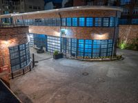 some dark blue windows in an industrial building with no one on the street to the right