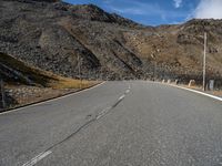 an empty road surrounded by mountains in the background with clouds and a sign saying no parking