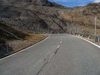 an empty road surrounded by mountains in the background with clouds and a sign saying no parking