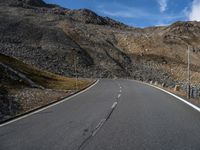 an empty road surrounded by mountains in the background with clouds and a sign saying no parking