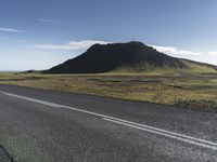 a person riding a bike down the road on a very sunny day in iceland, europe