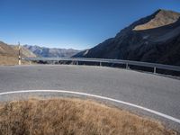 an empty mountain road next to a highway with several vehicles driving along it and in the background is mountains